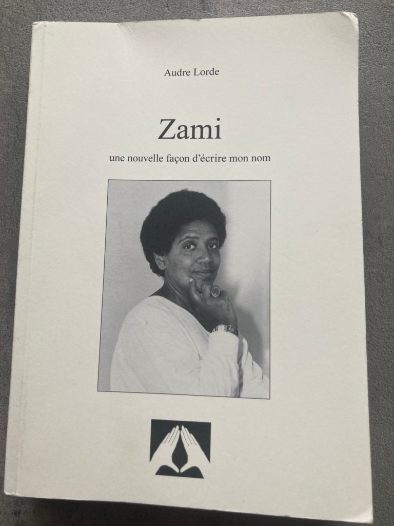 Couverture de "Zami". Fond blanc. Au centre, un portrait d'Audre Lorde se tenant le menton. Le sous-titre est : "une nouvelle façon d'écrire ton nom"